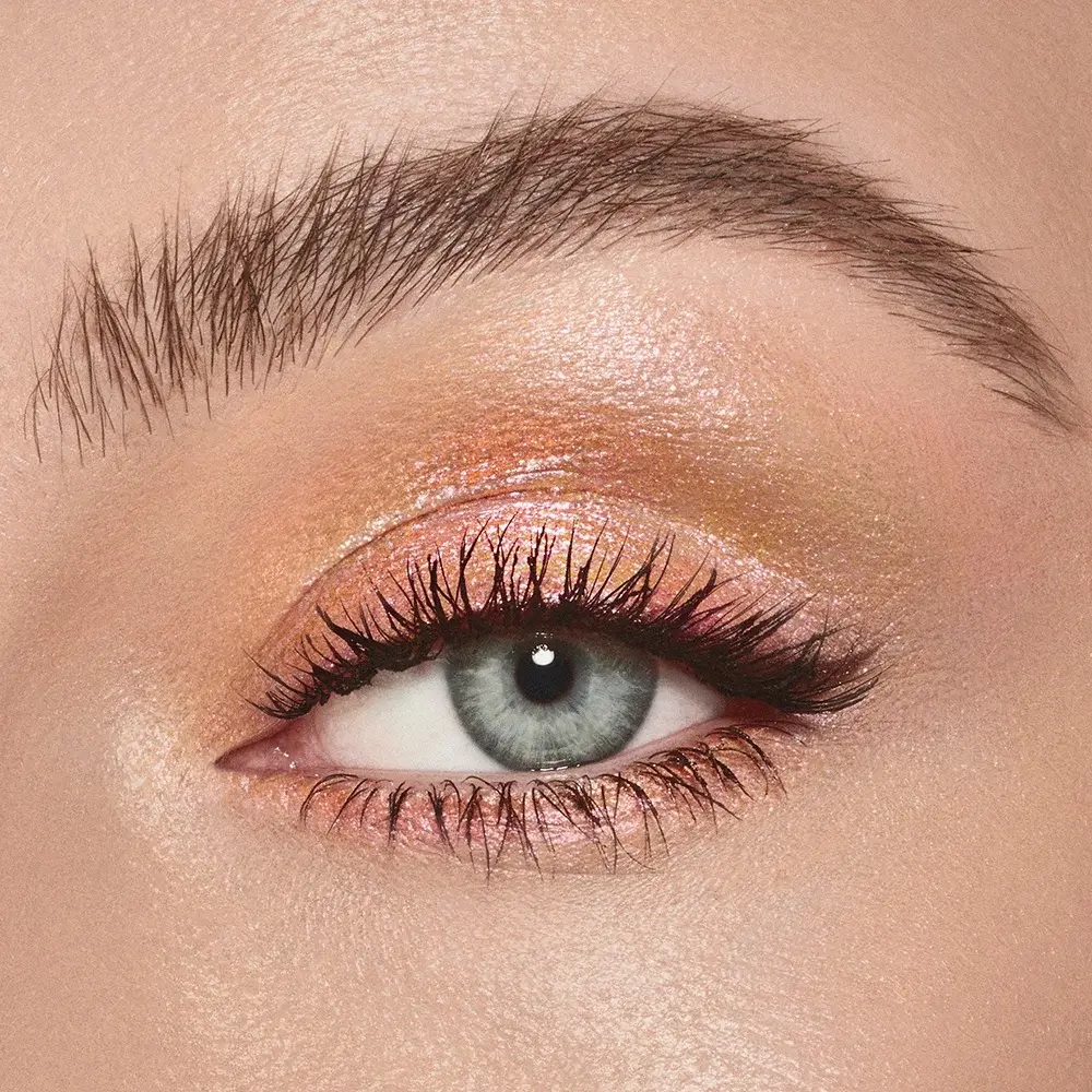 Close-up of an eyeshadow smudging brush with soft bristles and a rose-gold and dark crimson handle. 