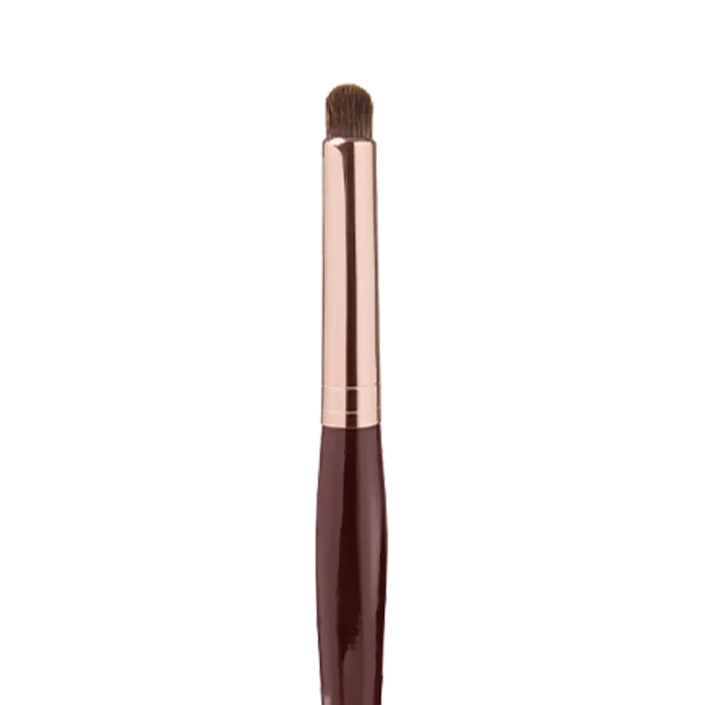 Close-up of an eyeshadow blending brush with soft bristles and a rose-gold and dark crimson handle. 